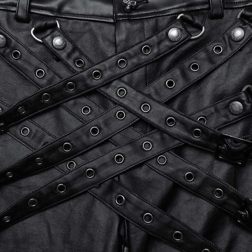Close-up of Mordanthe Trousers featuring black fabric and unique strap design with eyelets for a bold look.