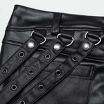 Close-up of Mordanthe Trousers showcasing the unique strap and grommet detailing on stylish black fabric.