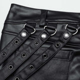 Close-up of Mordanthe Trousers showcasing the unique strap and grommet detailing on stylish black fabric.
